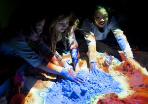 Children play with an augmented reality sandbox, which demonstrates how 2-D topographic maps show the 3-D shape of the land, during the 2013 "Can You Dig It?" event. Florida Museum of Natural History photo by Kristen Grace