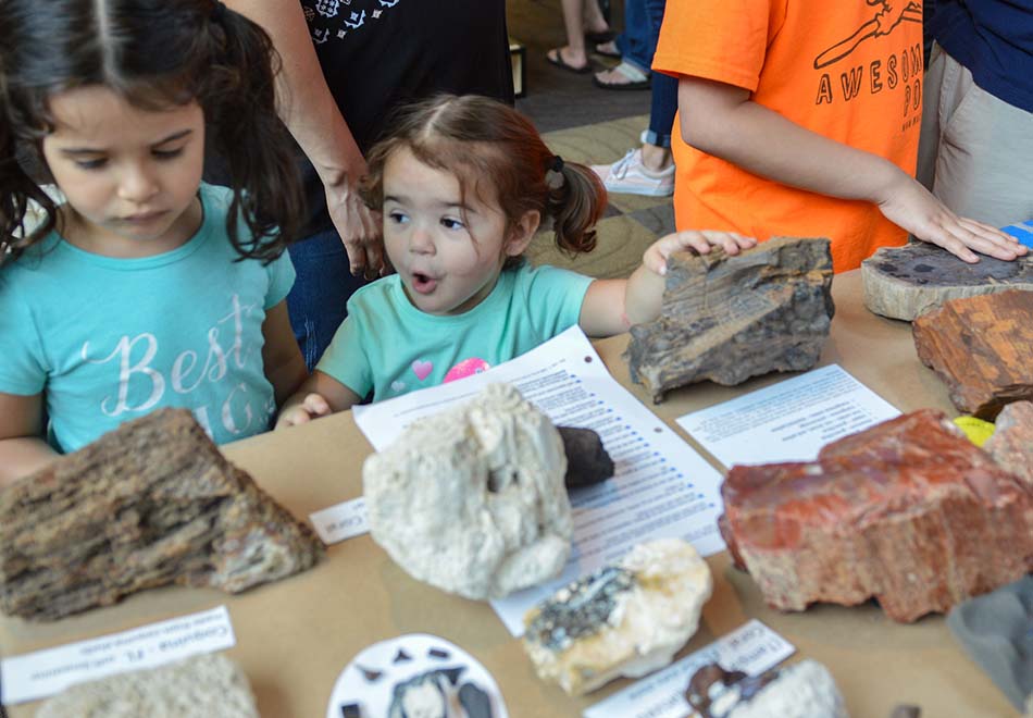 two girls touching big rocks on a table