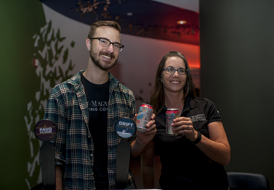 man and woman smiling holding beer cans