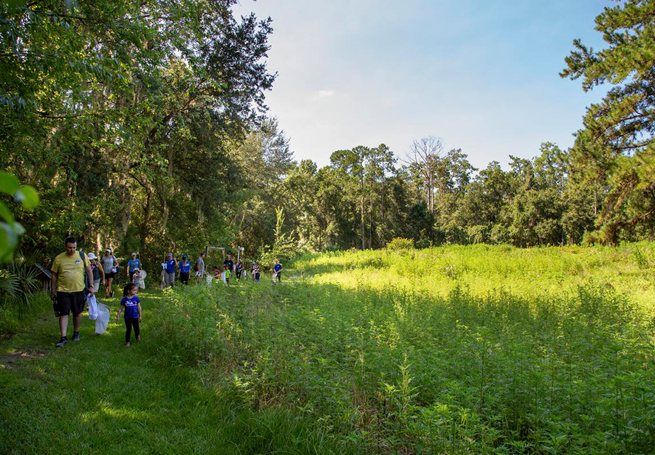 group of adults and children walking around a path at the edge of a field