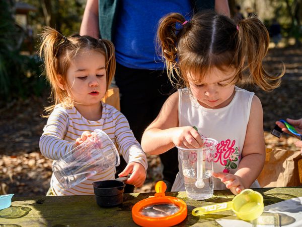 children using cups and measuring cups and spoons with water.