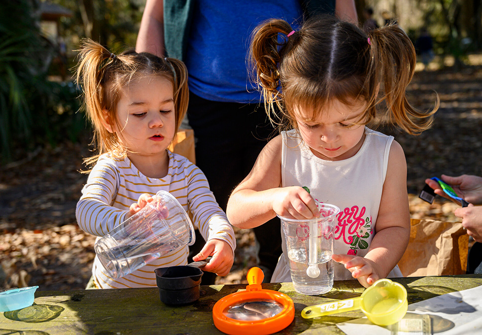 children using cups and measuring cups and spoons with water.