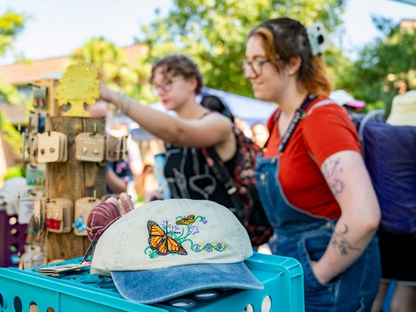two people are out of focus browsing at a table of gift items at an open air market of some kind