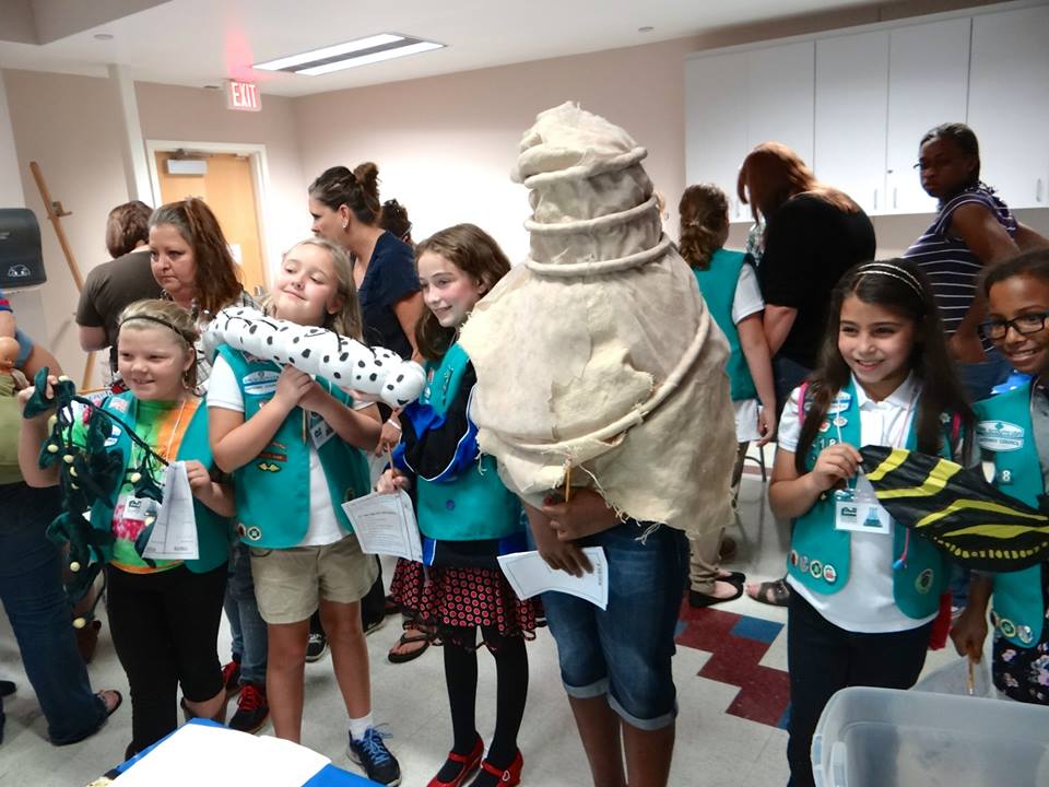 girl scouts holding models of butterfly metamorphosis stages