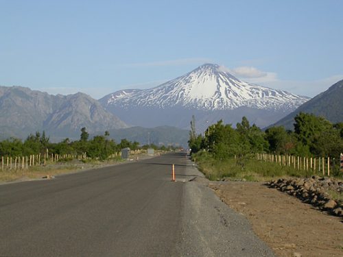 a snowcapped mountain with an empty road leading towards it