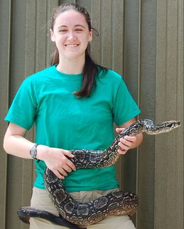 person in a green shirt holding a large snake