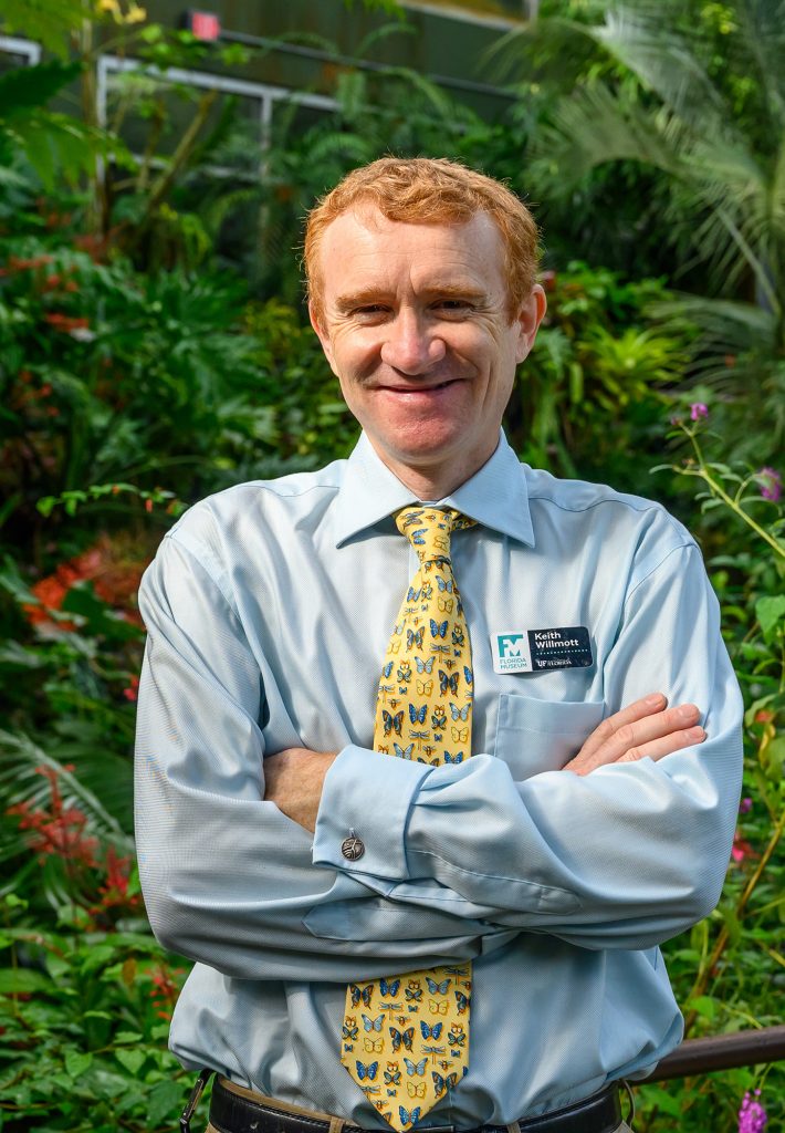 Portrait of smiling Keith Willmott, standing in butterfly rainforest with arms crossed