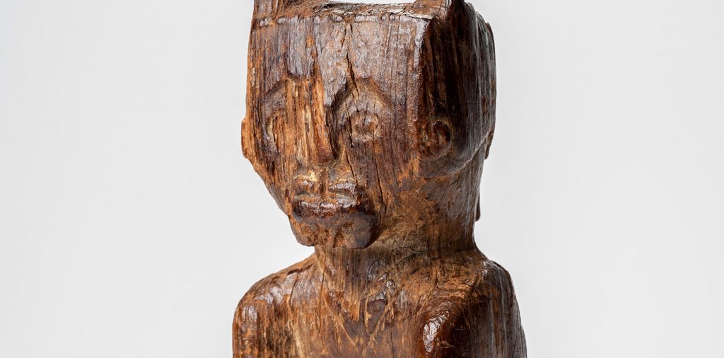 Close-up showing the face of the carved wooden feature. Eyes, nose, mouth, and ears are well-defined.