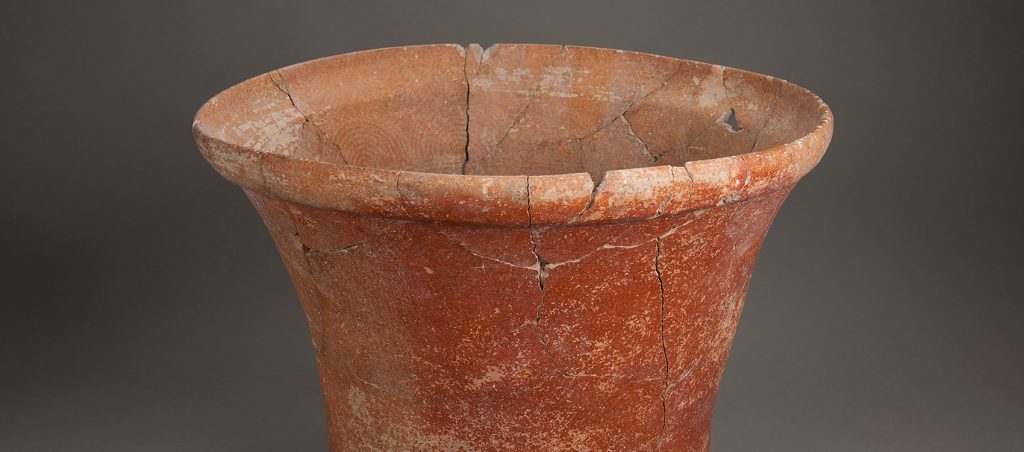 Terra-cotta colored pot with a curved lip and a faint circular pattern visible on the interior. Fine cracks can be seem where the bucket was reassembled