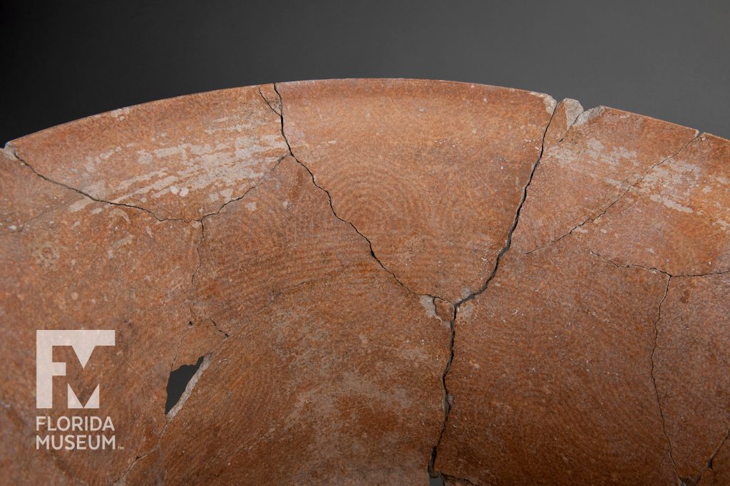 close up of interior of the bucket showing the fine cracks where the bucket was reassembled as well as the faint curricular pattern in the clay