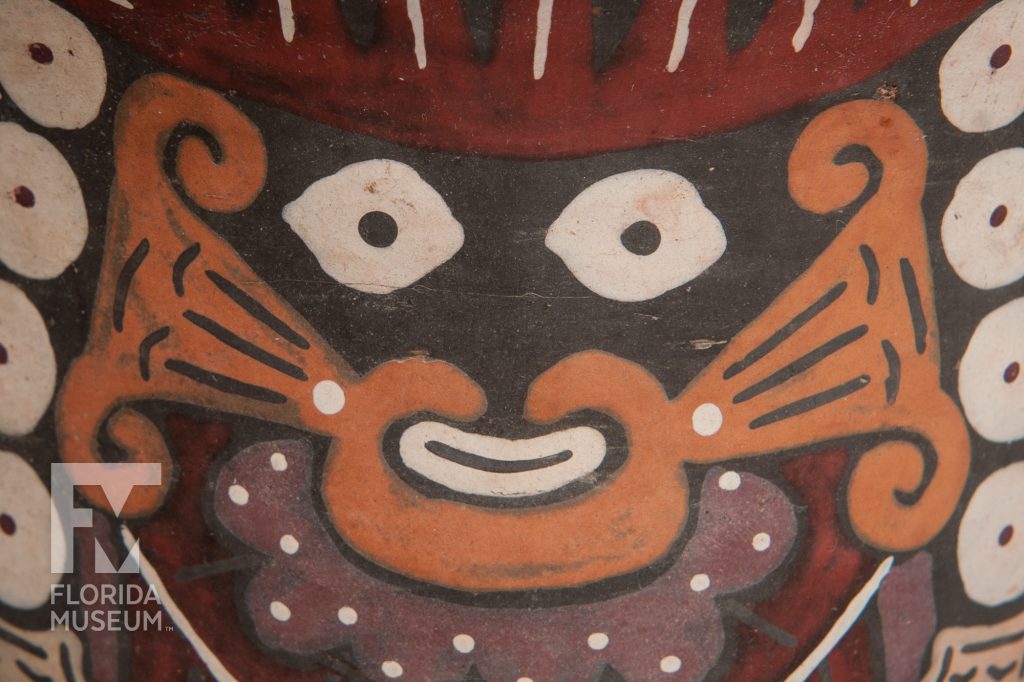 close up of bowl painted with figure in black, orange, purple and red