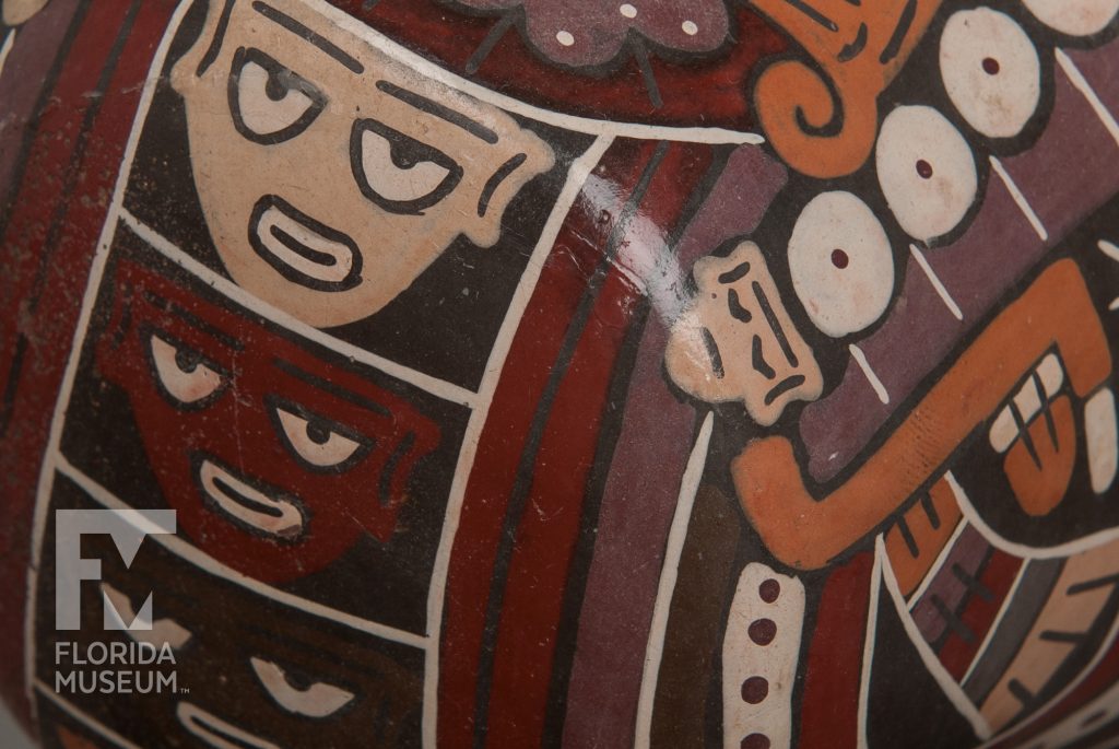close up of bowl bottom of the bowl painted with faces in tan, red, and brown.