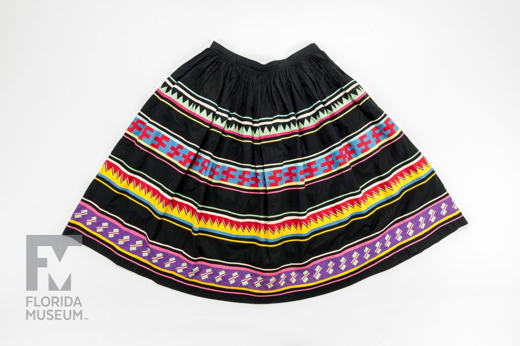 photographed from above - Patchwork Skirt placed flat with the skirt fanned out. Fabric alternates between horizontal black and multicolored patchwork stripes.