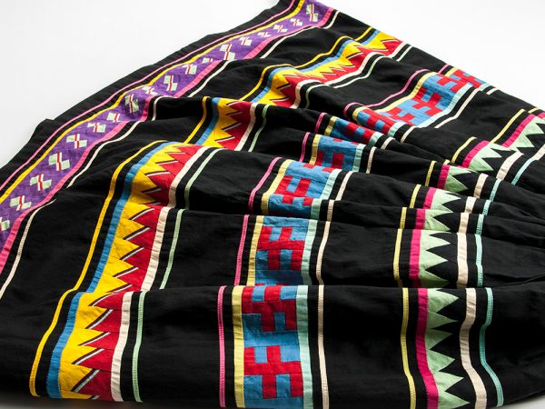 Woman’s Patchwork Skirt. Fabric alternates between black and multicolored patchwork stripes.