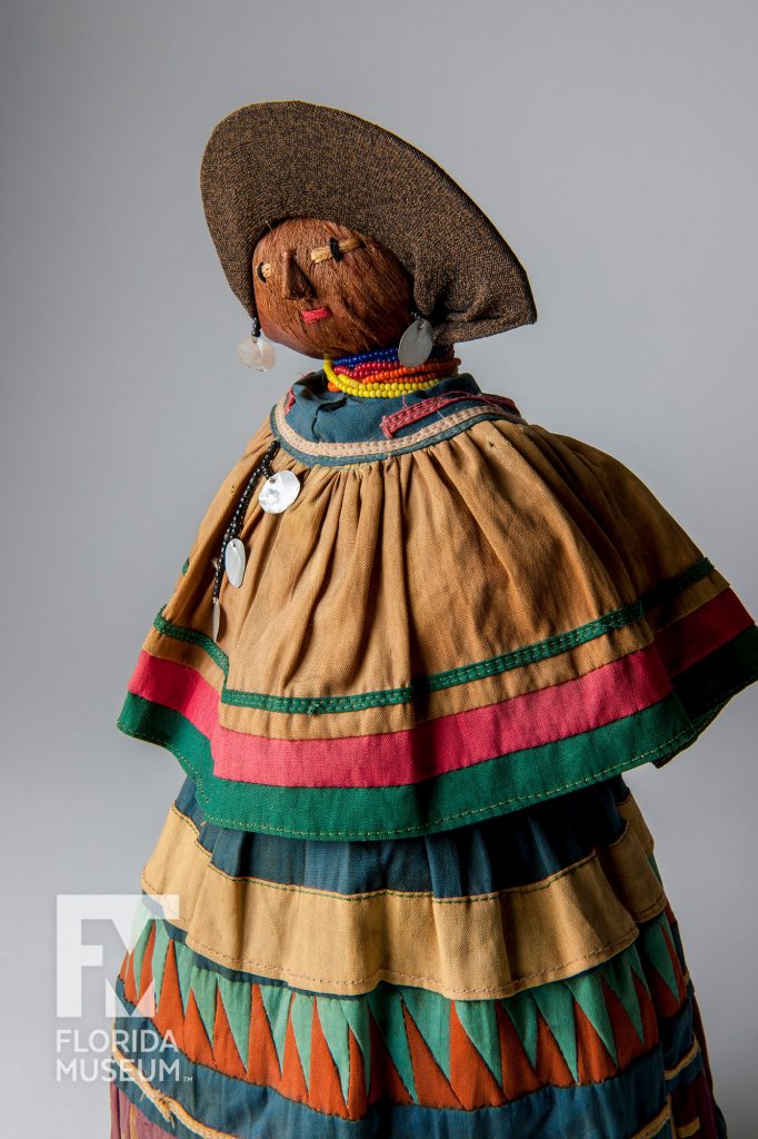 close up of doll in bright clothing wearing traditional patchwork clothing and jewelry.