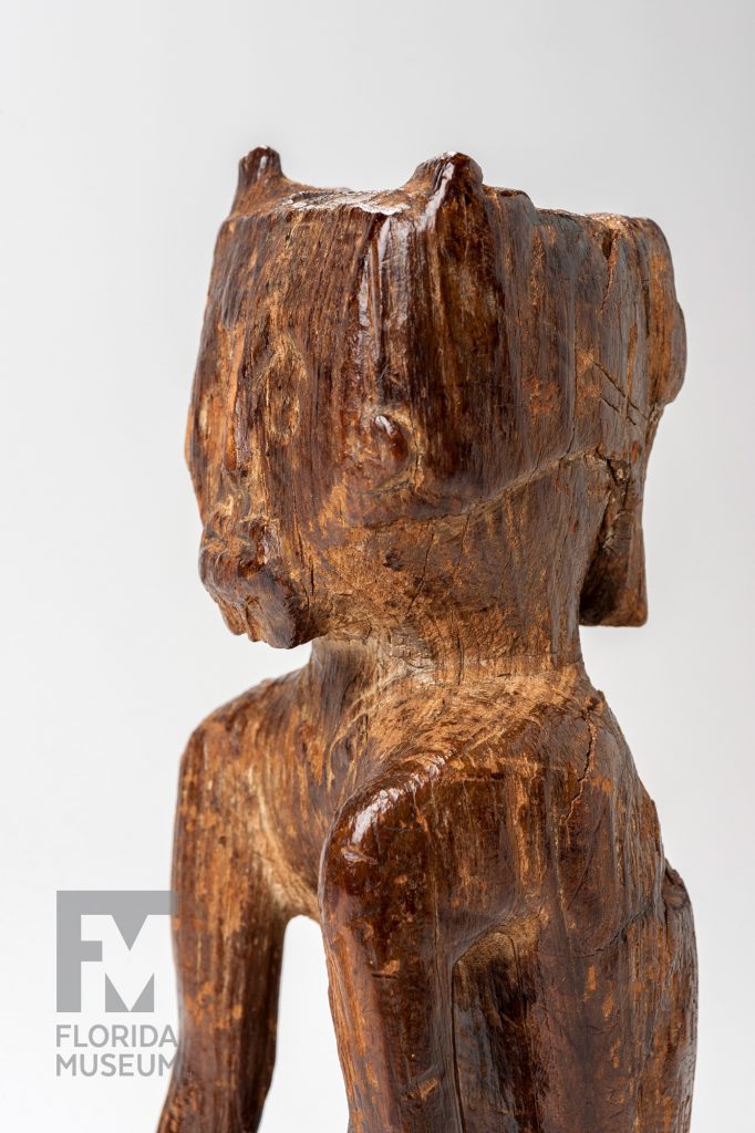 Close-up showing the face of the carved wooden figurine photographed from the side.