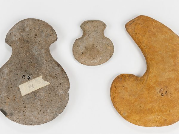 three stone hoes of various sizes, shapes, and color. Each has a wide semicircular base and a sharper tip.