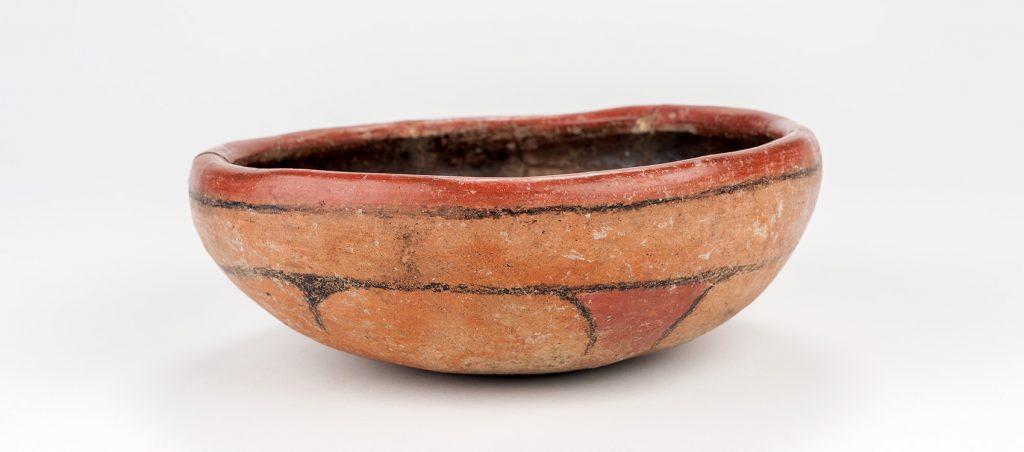 shallow bowl with thick sides painted with simple designs in two shades of terra-cotta and black
