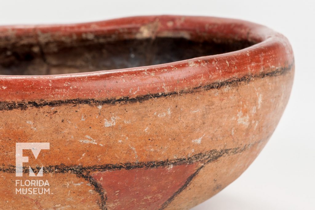 lose up of shallow bowl with thick sides painted with simple designs in two shades of terra-cotta and black
