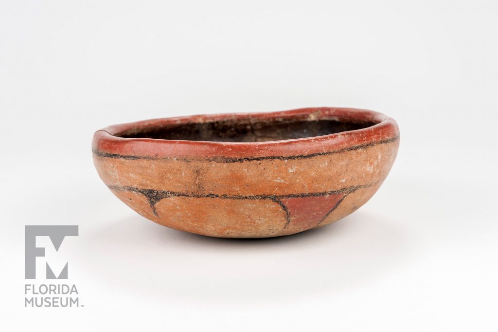 shallow bowl with thick sides painted with simple designs in two shades of terra-cotta and black
