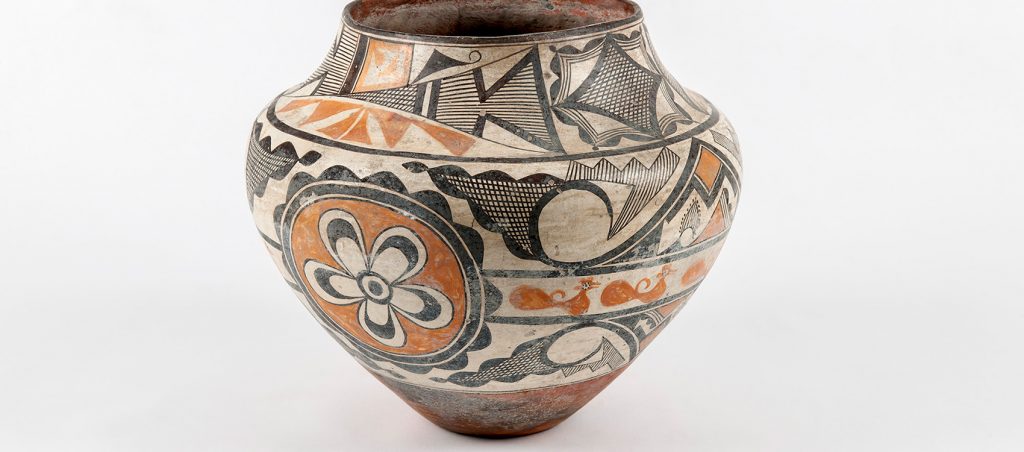 vase painted with tan, black and Terra-cotta colored flowers, birds, and geometric patterns.