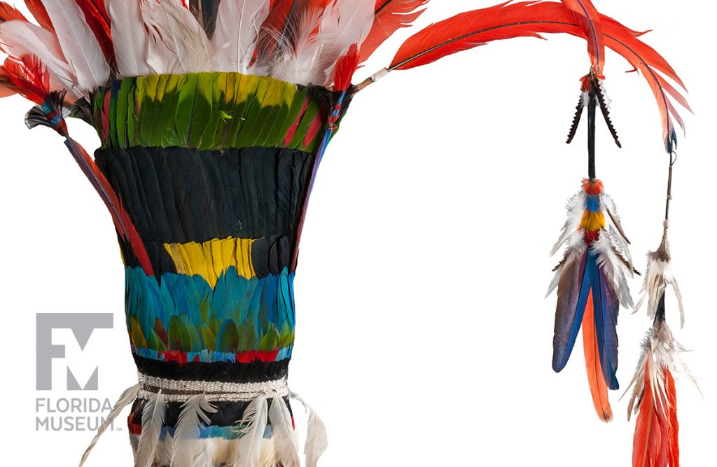 close up of the headdress showing the feather tassels and the rows of red, white, green blue-black and yellow feathers.