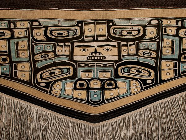 woven blanket with motifs in tan, black, and blue