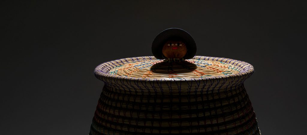 dramatically lit basket top with doll head in the center of the lid