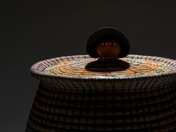 dramatically lit basket top with doll head in the center of the lid