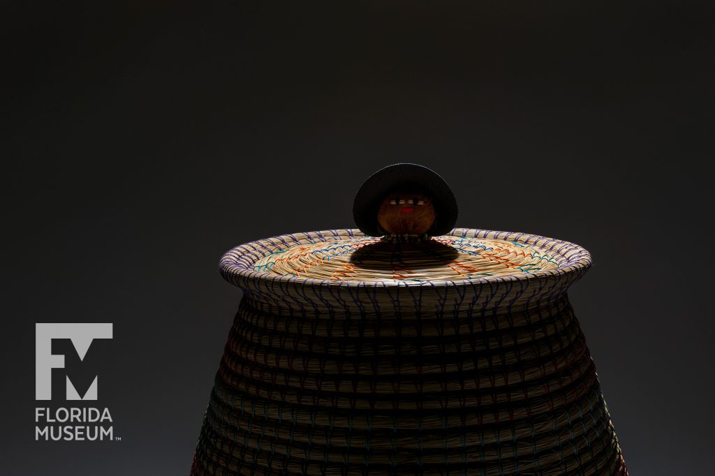 dramatically lit basket top with doll head in the center of the lid