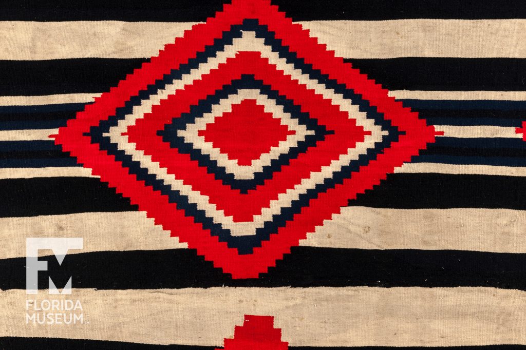 close up of woven black, tan, and red wearing blanket