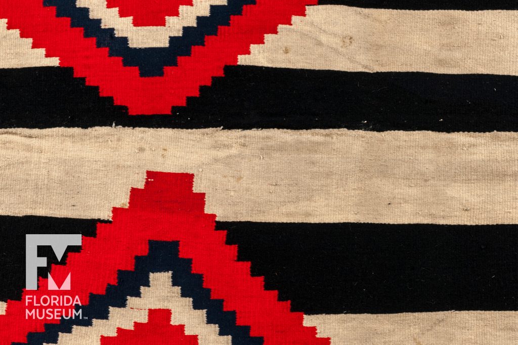 close up of woven black, tan, and red wearing blanket