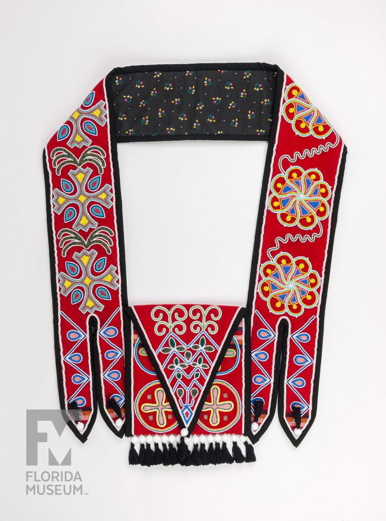 The front of a Seminole Shoulder Bag made from red fabric and heavily decorated with designs sewn in seed beads