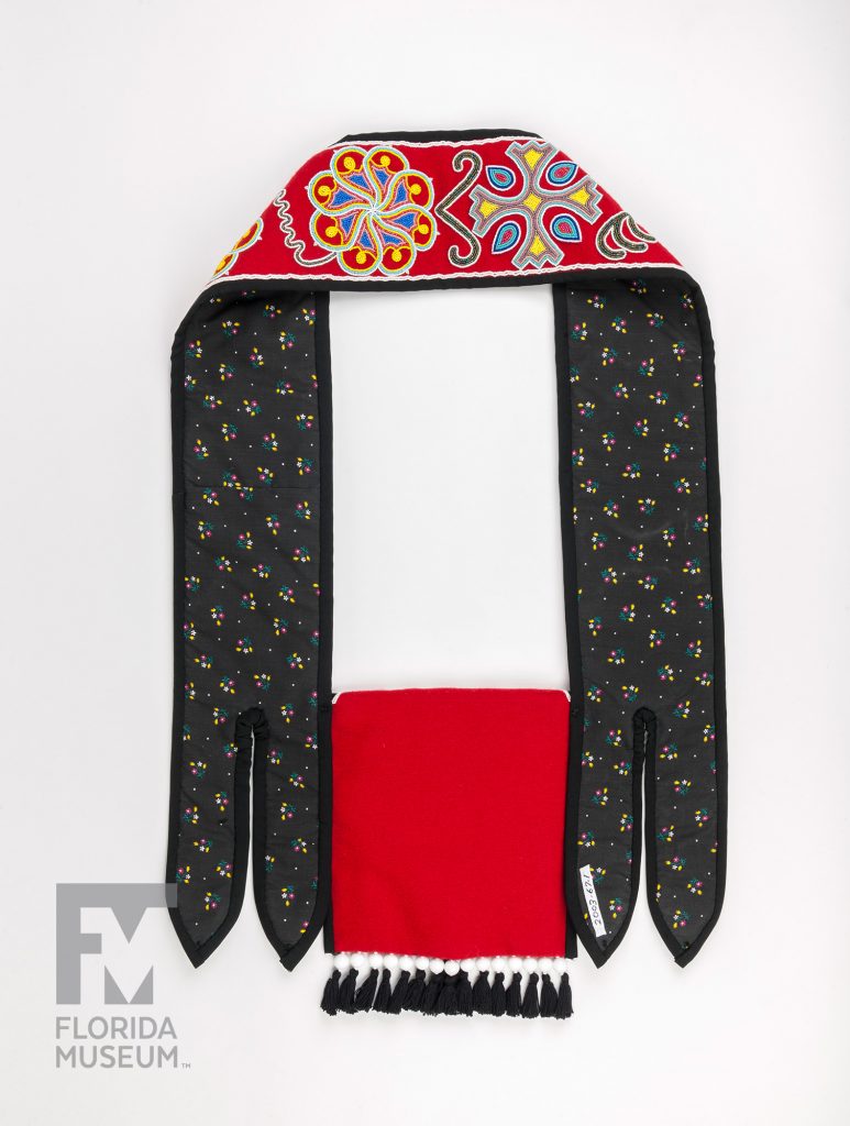 The front of a Seminole Shoulder Bag made from red fabric and heavily decorated with designs sewn in seed beads