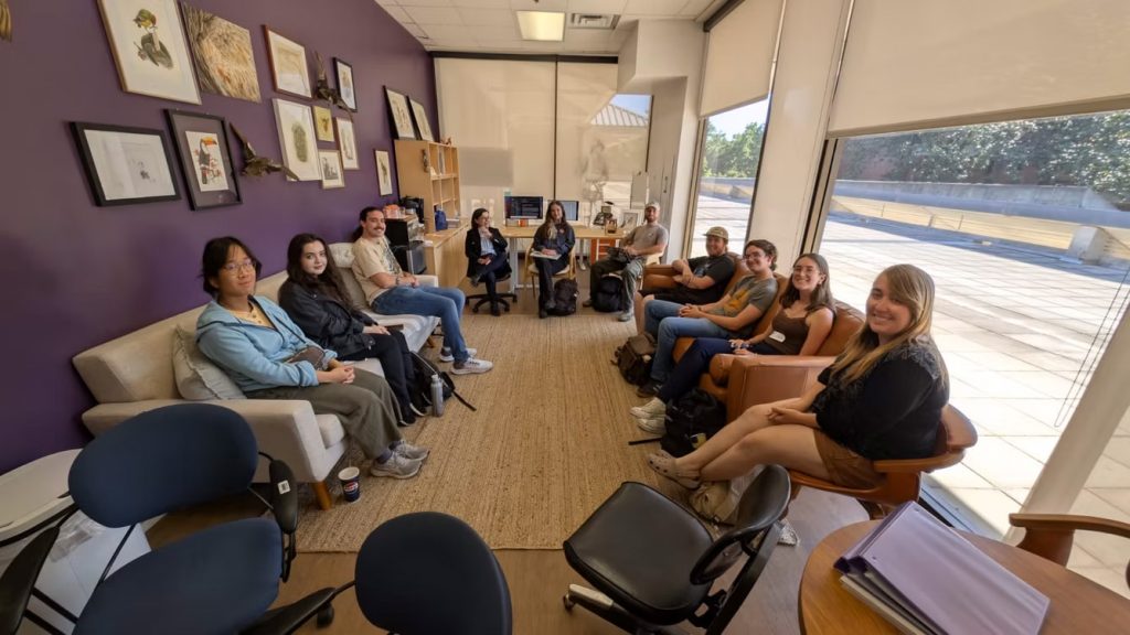 large group of people sitting in a circle in an office
