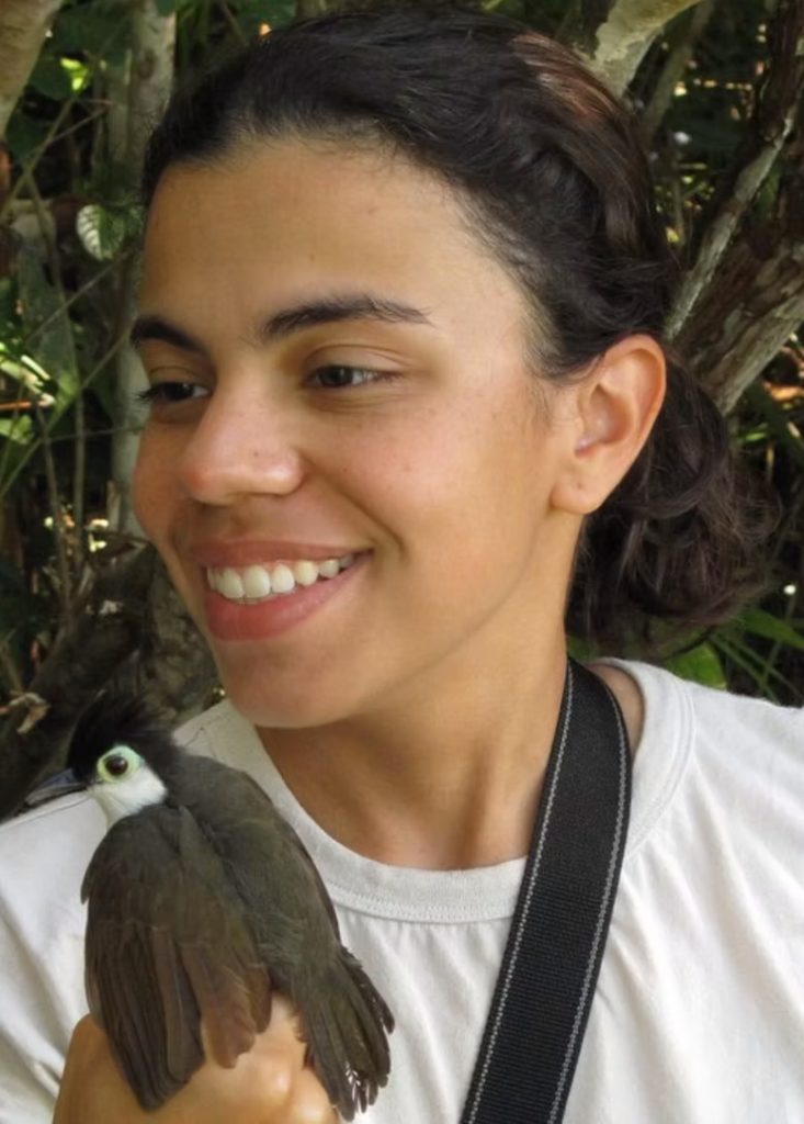 Glaucia Del-Rio holding a gray bird with a black crest and a light blue ring around its eye