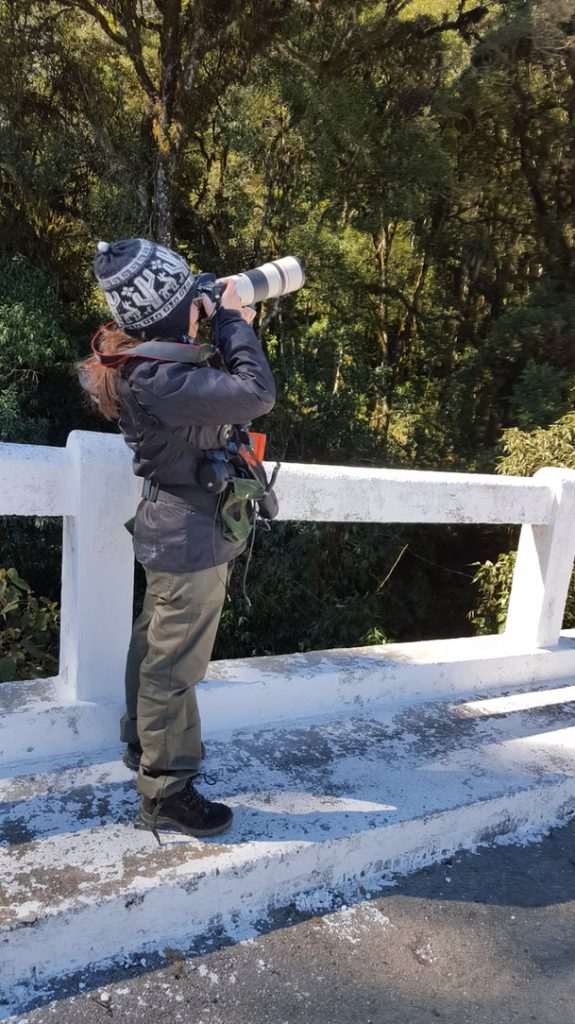 Glaucia Del-Rio standing a bridge using a camera with a long zoom lens