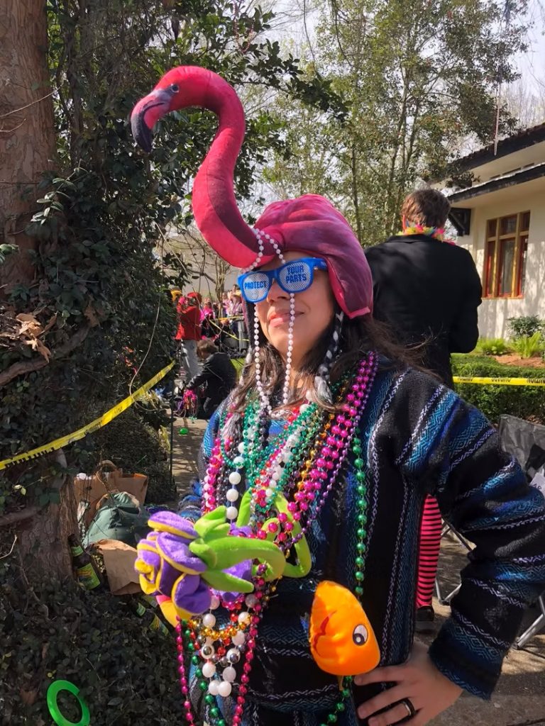 research wearing many Mardi Gras beads and a pink flamingo hat