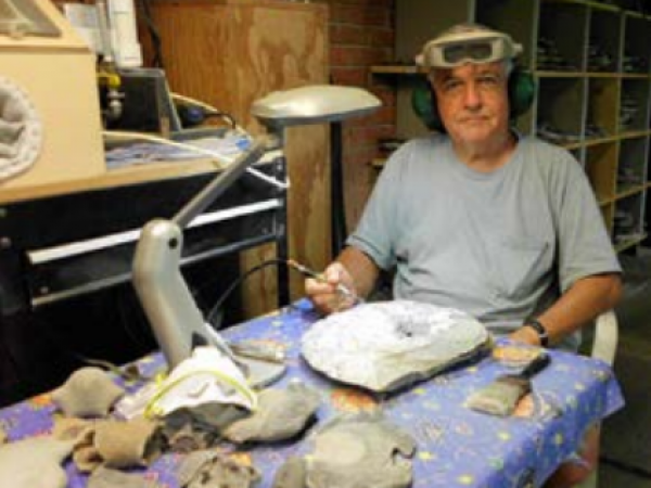 George preparing a Cretaceous ammonite hecollected in Alabama in his home prep lab. Photo courtesy 
of George Martin
