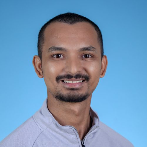 An image of a man smiling. The background is blue.