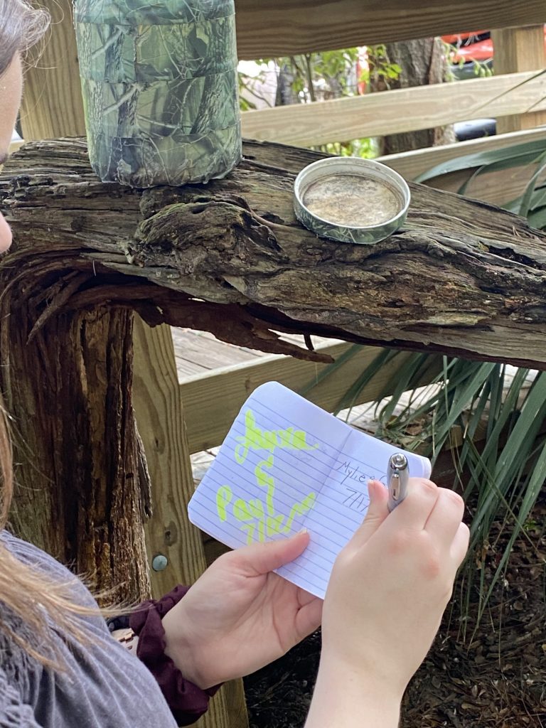 Person looking at phone, the Florida Museum can be seen behind her