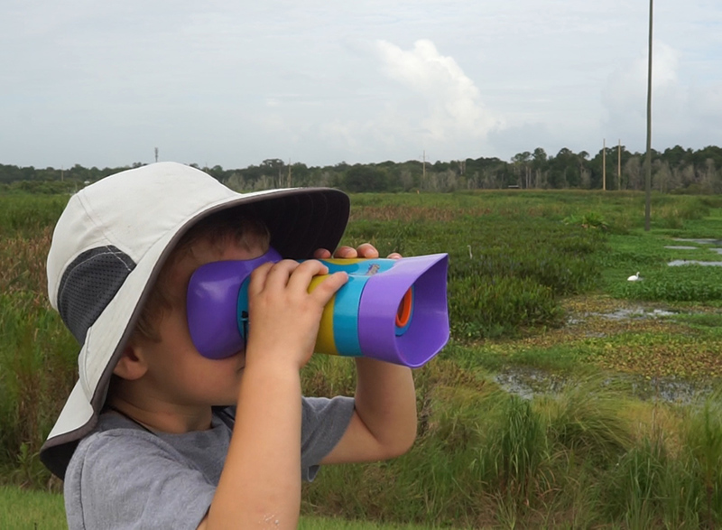 child looking through brightly colored binoculars