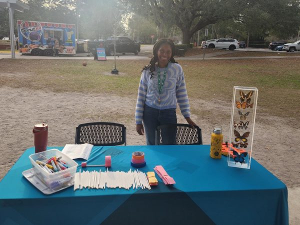 Ruthie Petit-Frere stand behind a table set with hoop glider craft supplies and smiles at the camera