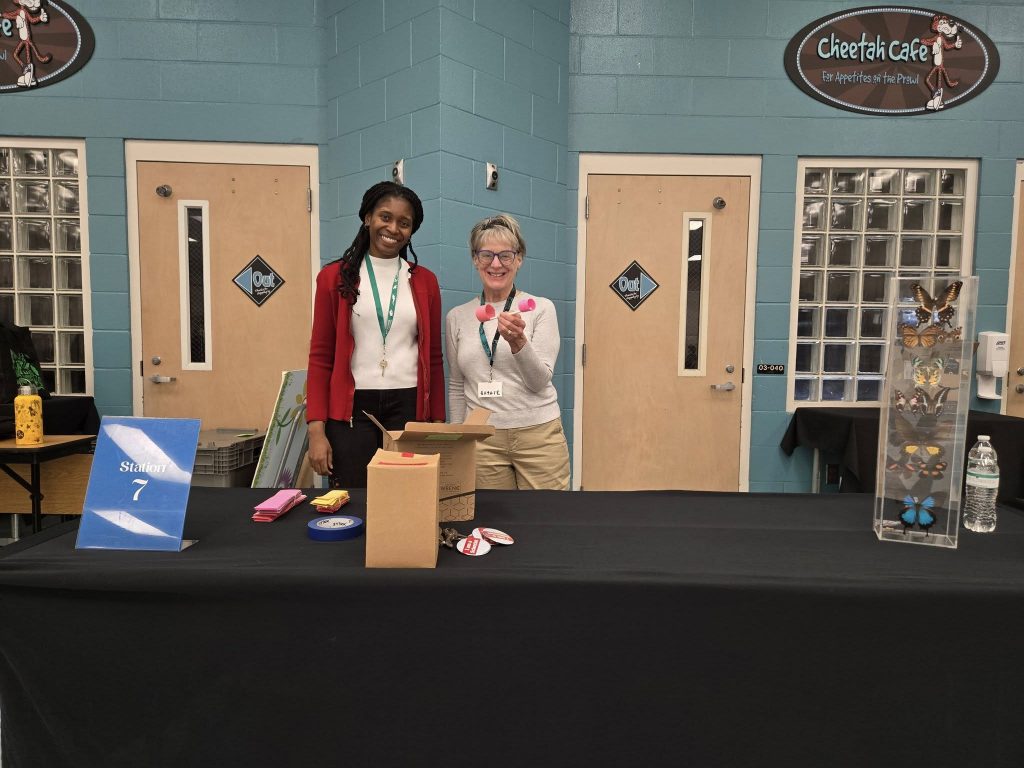 Two people behind a table with crafts to build a hoop glider