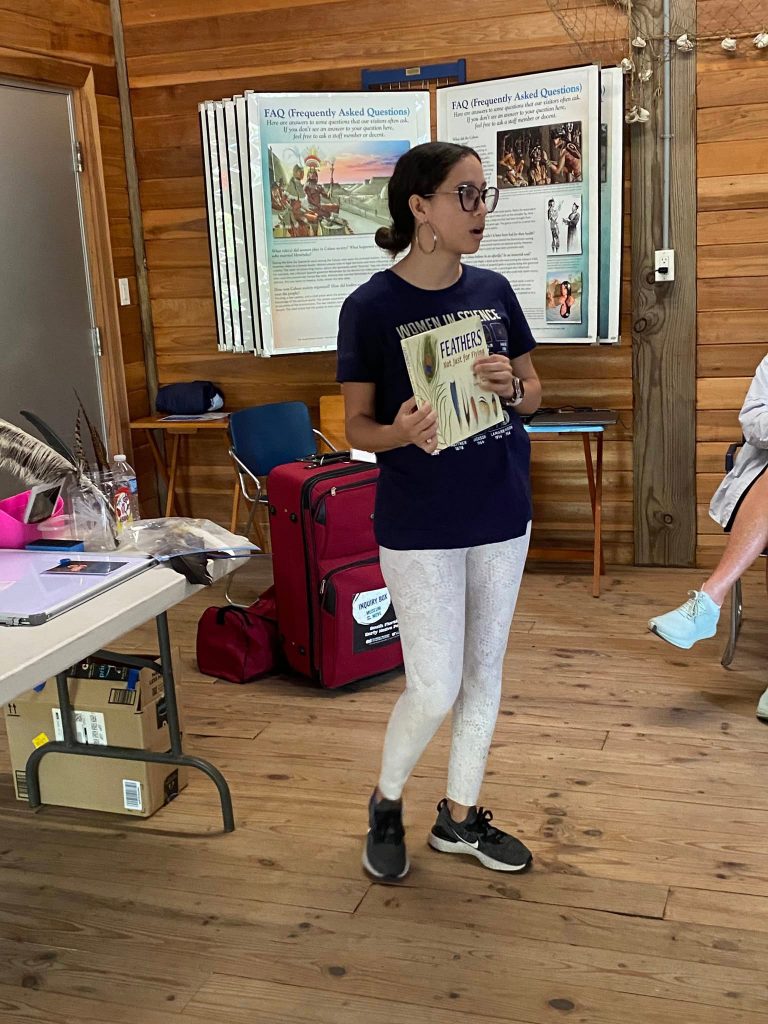 Janelle A. Peña-Jiménez shows the group of volunteers a book about feathers