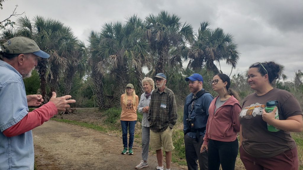 a group of people on a gravel pathway listening to a tour guide