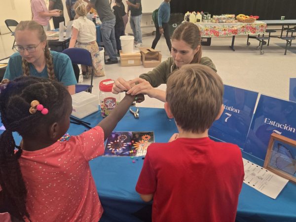 education team helping young students make beaded bracelets