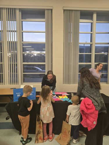 team member at the station 10 table speaking with young children