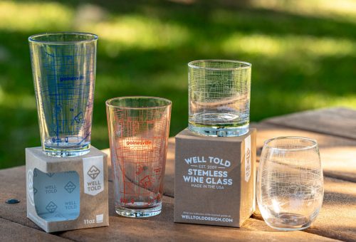 two pint glasses, a double old fashion glass, and a stemless wine glass etched with road maps of Gainesville. Some of the maps are blue or orange