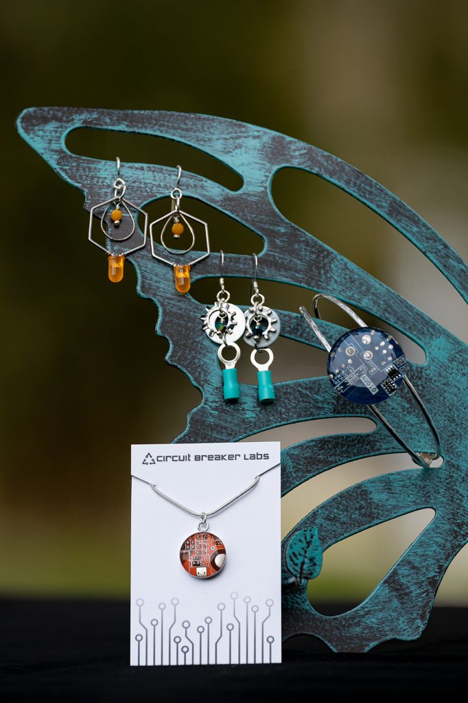 earrings, necklace and bracelet displayed against a metal butterfly wing